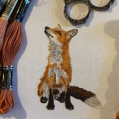 the fox is sitting on the table next to scissors and thread