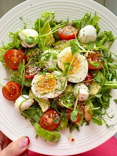 a salad with hard boiled eggs, tomatoes and lettuce on a white plate