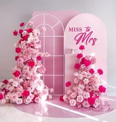 pink flowers are arranged in front of a sign for the miss and mrs contest on display