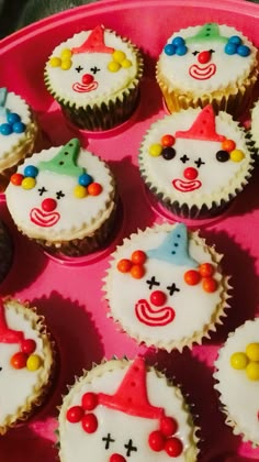 cupcakes decorated with clown faces on a pink tray