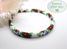 a close up of a bracelet on a white surface with a flower in the background