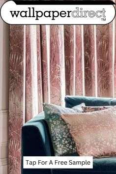 a blue couch sitting next to a window covered in pink curtains