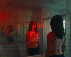 a woman standing in front of a mirror with red light coming from her chest and back