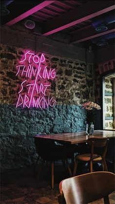 a neon sign that reads stop thinking before drinking on the side of a stone wall