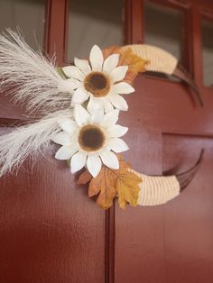 a wreath with fake flowers and feathers on the front door to decorate it for fall