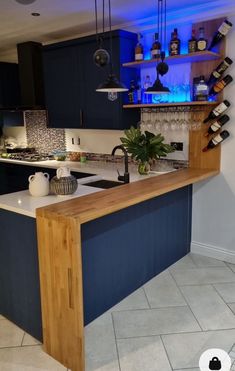 a kitchen with blue cabinets and an island in the middle is lit up by lights