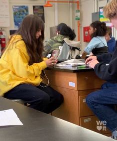 two young people sitting at a desk with headphones on