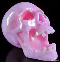 a pink skull with its mouth open on a black surface