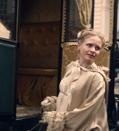 a woman standing in front of an old fashioned train with her hands on her hips