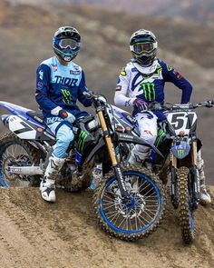 two people riding dirt bikes on top of a hill