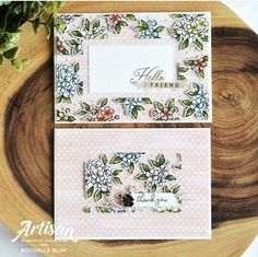 two cards with flowers on them sitting on top of a wooden table