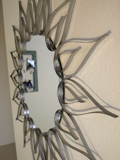 a decorative mirror hanging on the side of a wall next to a white wall with a silver frame