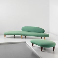 two green couches sitting next to each other on a white floor in an empty room