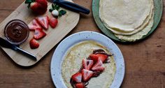 two plates with pancakes, strawberries and chocolate sauce on them next to each other