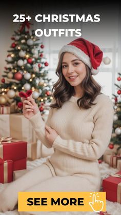 a woman sitting in front of a christmas tree wearing a santa hat and holding presents