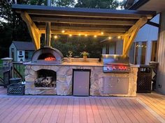 an outdoor bbq grill with lights on the outside and wood decking around it