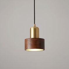 a wooden light fixture hanging from a metal hook on a gray wall with a black cord