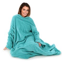 a woman is sitting on the floor wrapped in a blue blanket and smiling at the camera