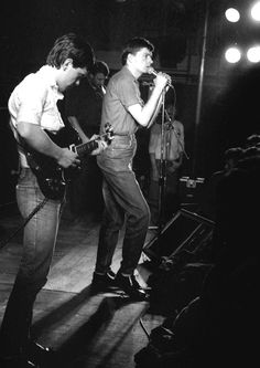 black and white photograph of two young men singing into microphones in front of an audience