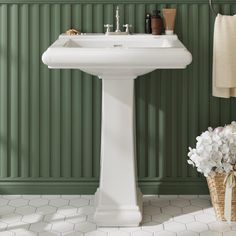 a white pedestal sink sitting next to a green wall