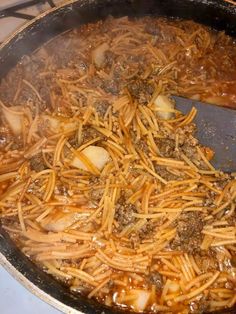 some food is being cooked in a large pan on the stove with a spatula