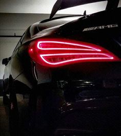 the rear end of a sports car with its lights on