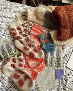 several knitted mittens and gloves laying on a bed