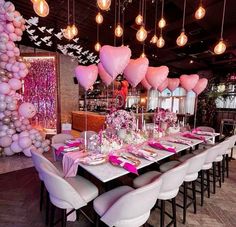 a table set up for a party with pink and white balloons