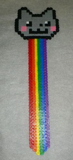 a cat head made out of beads on top of a t - shirt with a rainbow in the middle