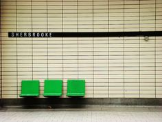 two green chairs sitting in front of a subway sign on the side of a wall