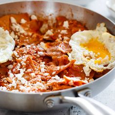 two eggs are being cooked in a pan with meat and cheese on the side,