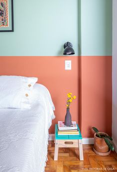 a bedroom with a bed, nightstand and painting on the wall behind it in pastel colors