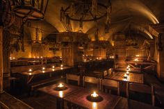 a dimly lit restaurant with wooden tables and candles on the tables in front of them