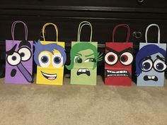 five paper bags with cartoon characters painted on them, all lined up in a row