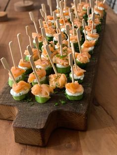 small appetizers are lined up on a wooden board with toothpicks sticking out of them