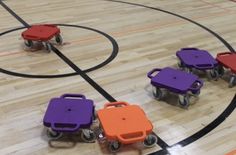 several plastic carts on a basketball court with orange and purple seats in the middle of it