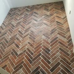 an empty bathroom with wood flooring and tile on the walls, in front of a toilet