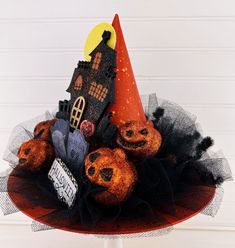 a halloween hat with pumpkins in it and a house on the top is decorated