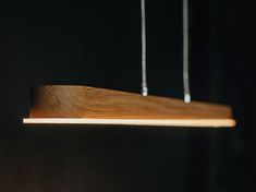 a wooden light fixture hanging from strings in a dark room with black walls and flooring