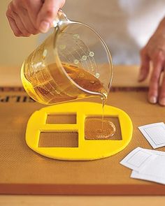 a person pours tea into a cup on top of a wooden table with papers