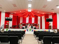 an empty auditorium with red and white striped walls, black chairs, and stage curtains