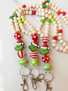 a bunch of beads and some keychains on a white table with two green and red christmas ornaments