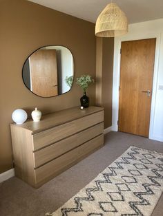 a room with a dresser, mirror and vase on the floor next to a door