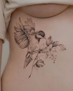 a woman's stomach with a bird and flower tattoo on it