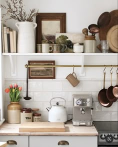 a kitchen with pots, pans and other items on the shelves above the stove