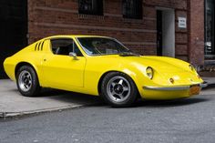 a yellow sports car parked in front of a brick building