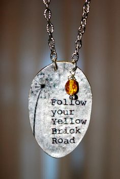 a necklace with a dandelion on it that says follow your yellow brick road