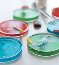 toothbrushes are sitting on colorful plates with toothpaste in the bottom one