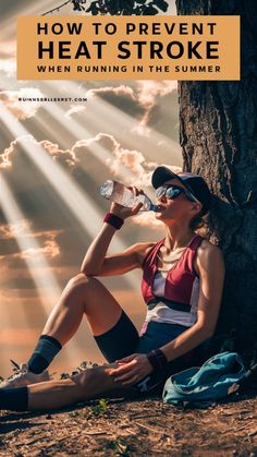 a woman sitting on the ground drinking water from a bottle with sunbeams in the background