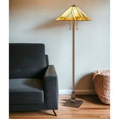 a lamp that is sitting on top of a wooden floor next to a gray couch